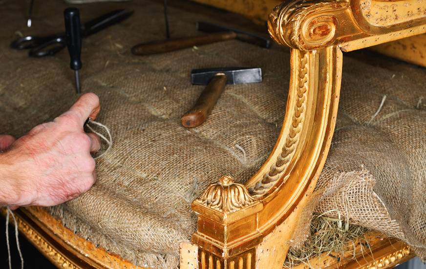 Ein Polsterer repariert ein altes Empire Sofa